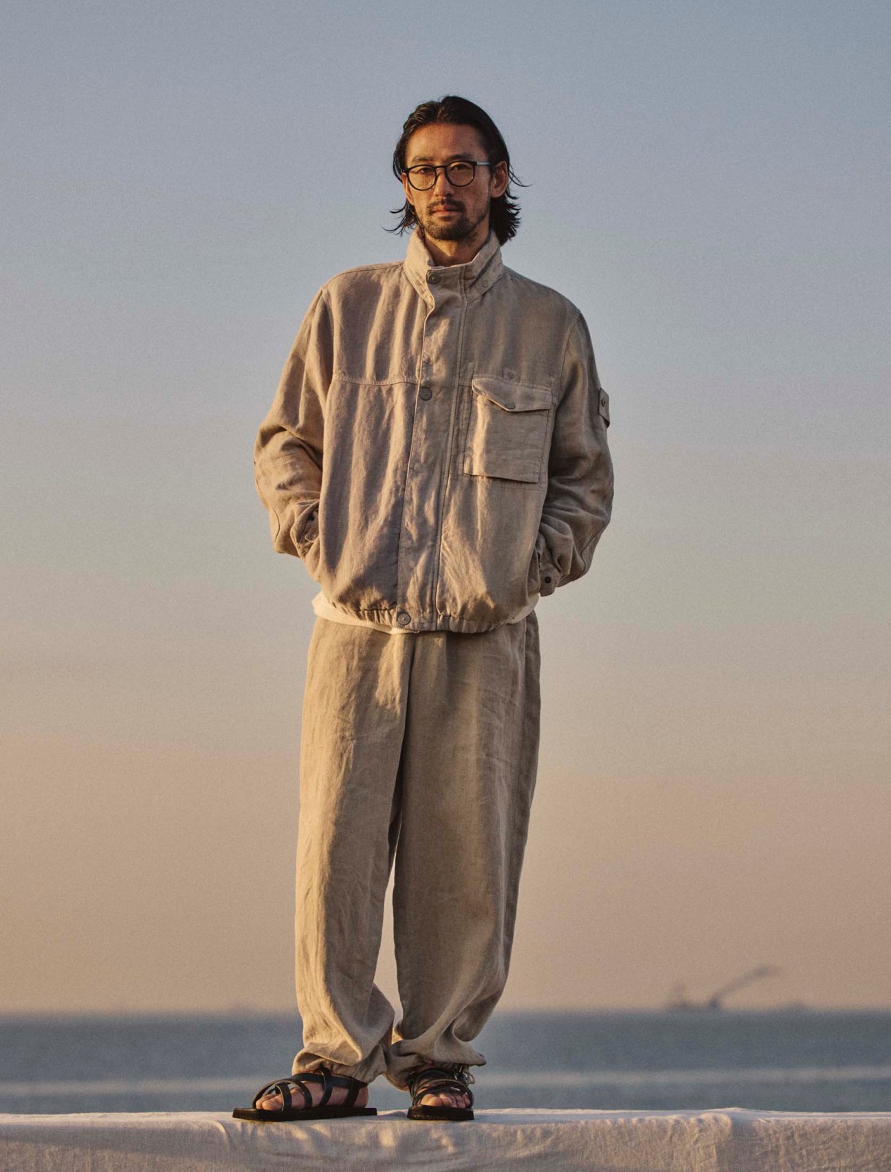 Jacket by Stone Island, thermal shirt by Polyploid, trousers by Aton, sandals by Hender Scheme, glasses by Mykita