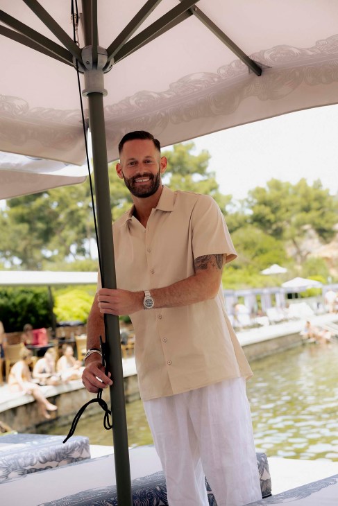 A man adjusting an umbrella at Lake Vouliagmeni