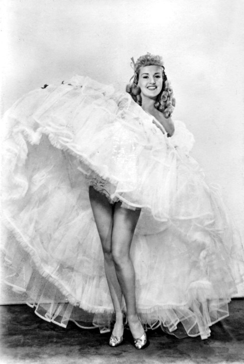 A woman revealing her legs from underneath a full skirt