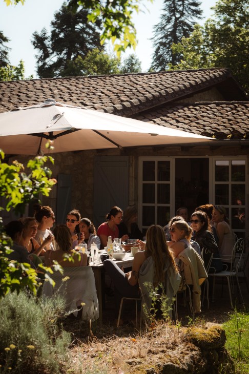 People eating outside as a table under an umbrella