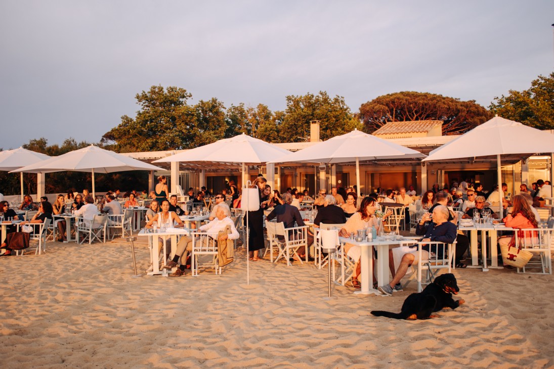 People sitting outside under umbrellas on the beach