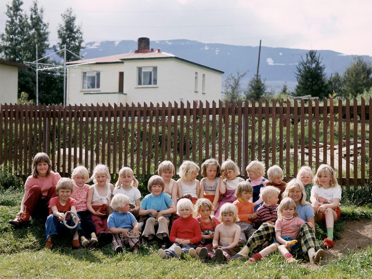 A group of young children sit on the grass