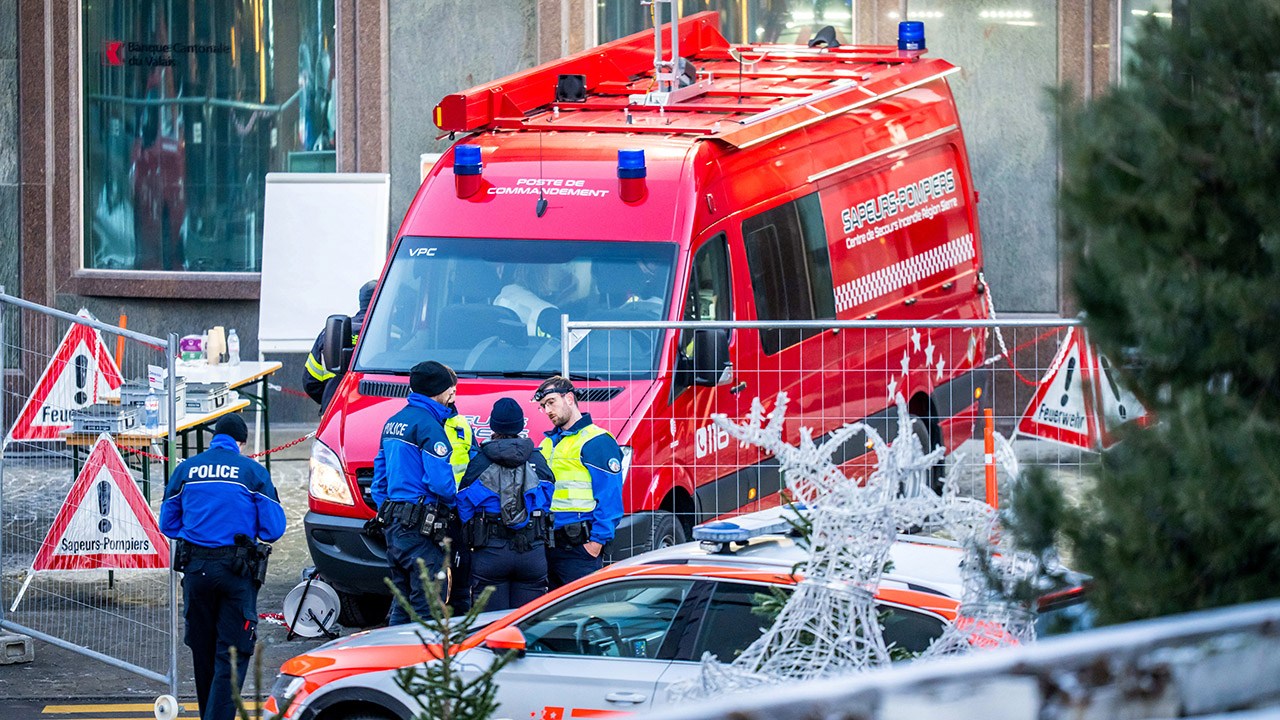 Police officers and rescuers stand next to a firefighters vehicle on the site of a fire that ripped through the bar Le Constellation in Crans-Montana on January 1, 2026. Several dozen people are presumed dead and around 100 injured after a fire ripped through a crowded bar in the luxury Swiss ski resort of Crans-Montana, Swiss police said on January 1, 2026. Police, firefighters and rescuers rushed to the popular resort, which is set to host the Ski World Cup from January 30, after the fire broke out in the early hours of New Year's Day. (Photo by MAXIME SCHMID / AFP via Getty Images)