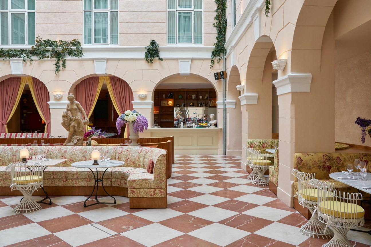 Hotel Bella Grande interior courtyard with floral seating bar draped curtains peach and white columns first floor windows terracotta and white checked tiles