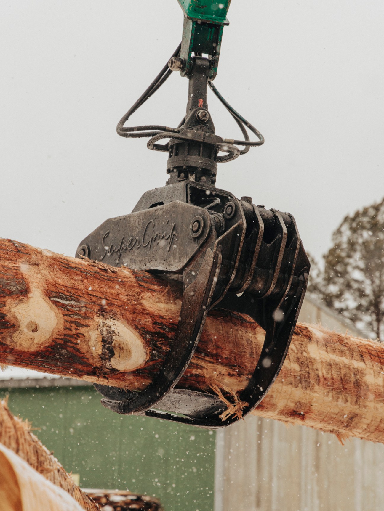 View of a snowy industrial facility with trucks and machinery at Kleniewski Tartak sawmill