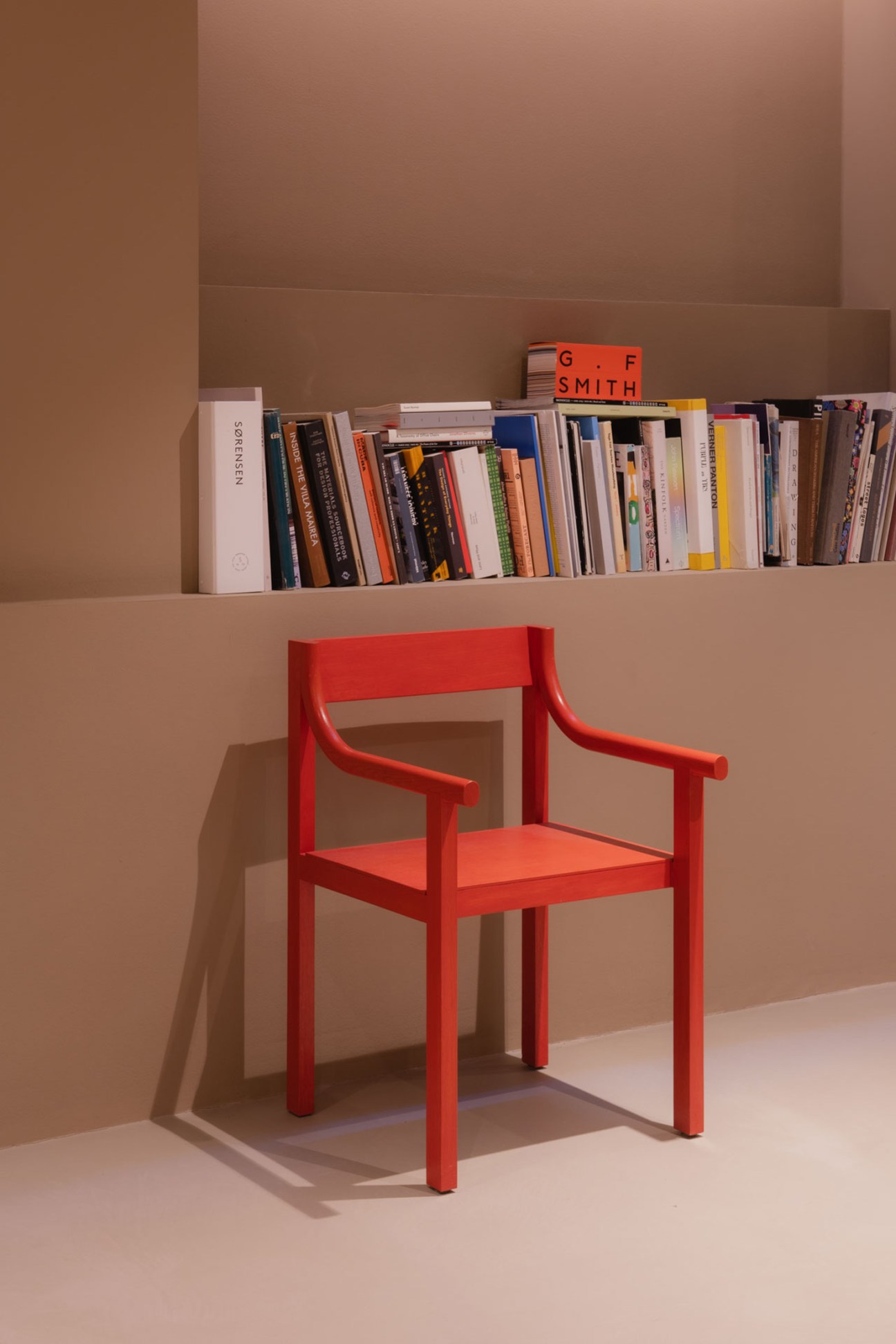A red chair in front of a row of books